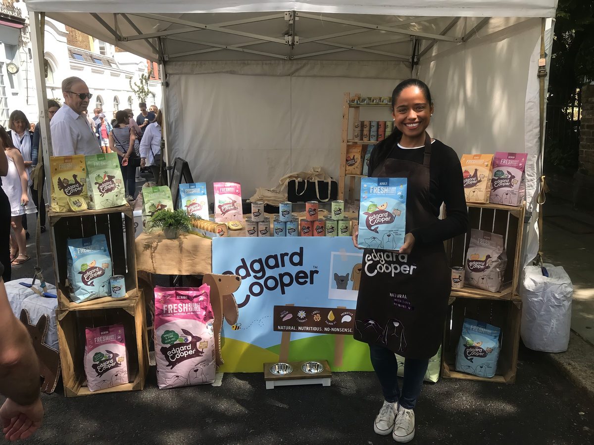 Edgard and Cooper brand ambassador holding a bag of pet food at a branded show stand