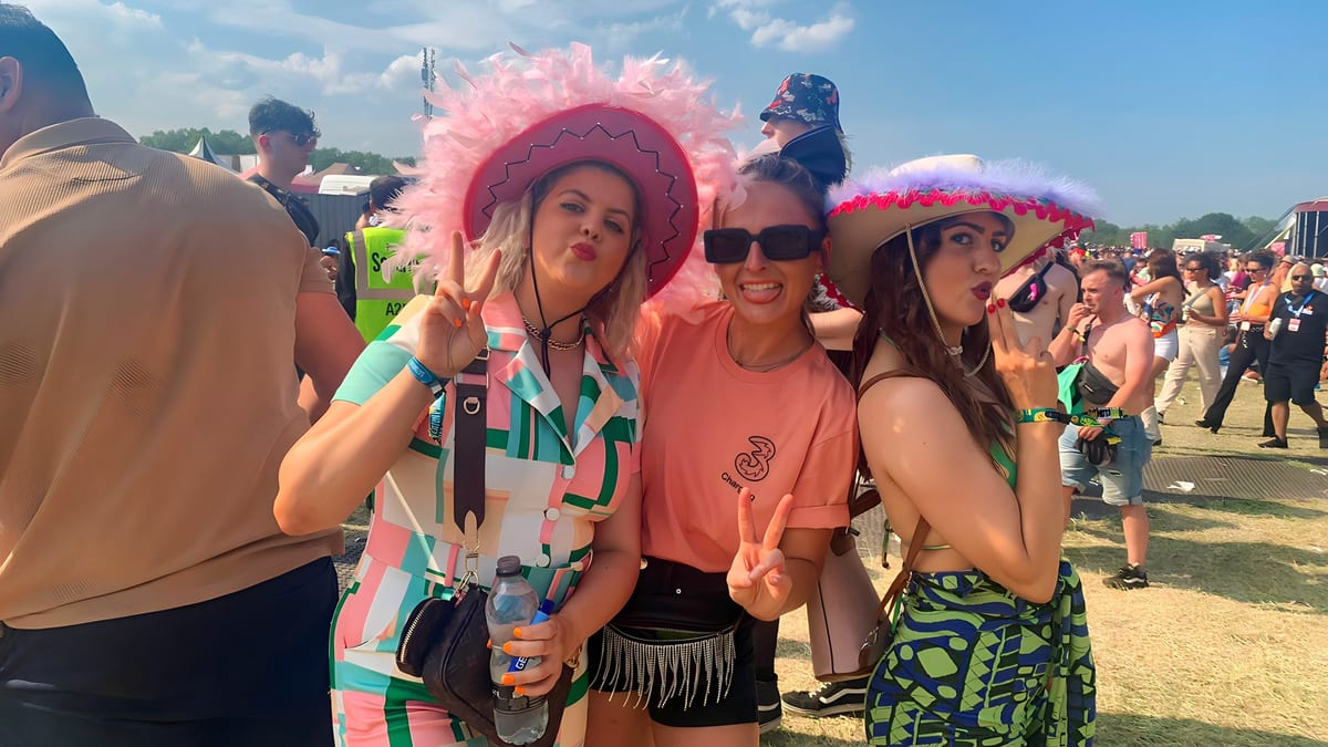 Festival-goers in party hats posing with a Three team member