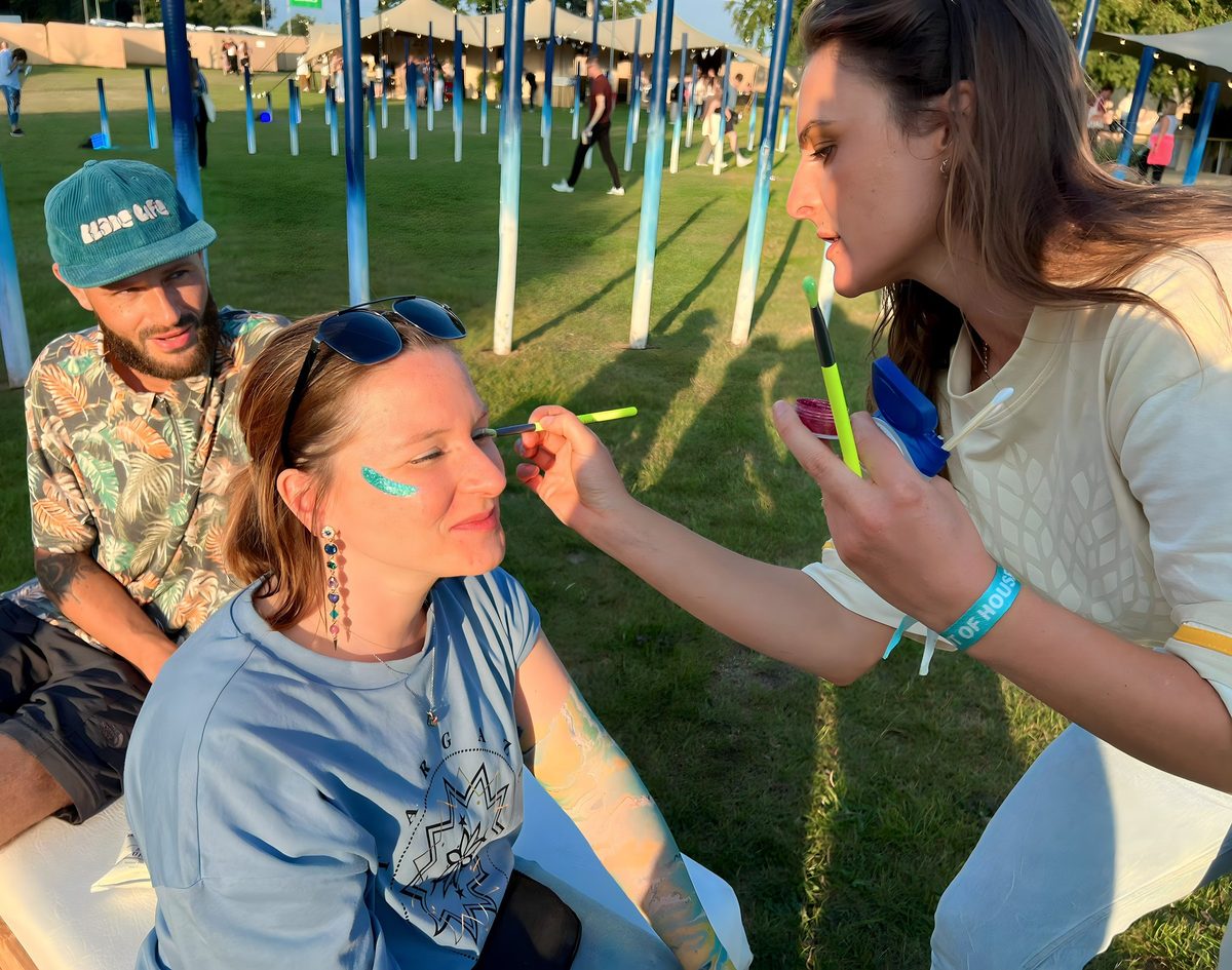 Executional brand ambassador applying eco-friendly glitter to a festival-goer's face