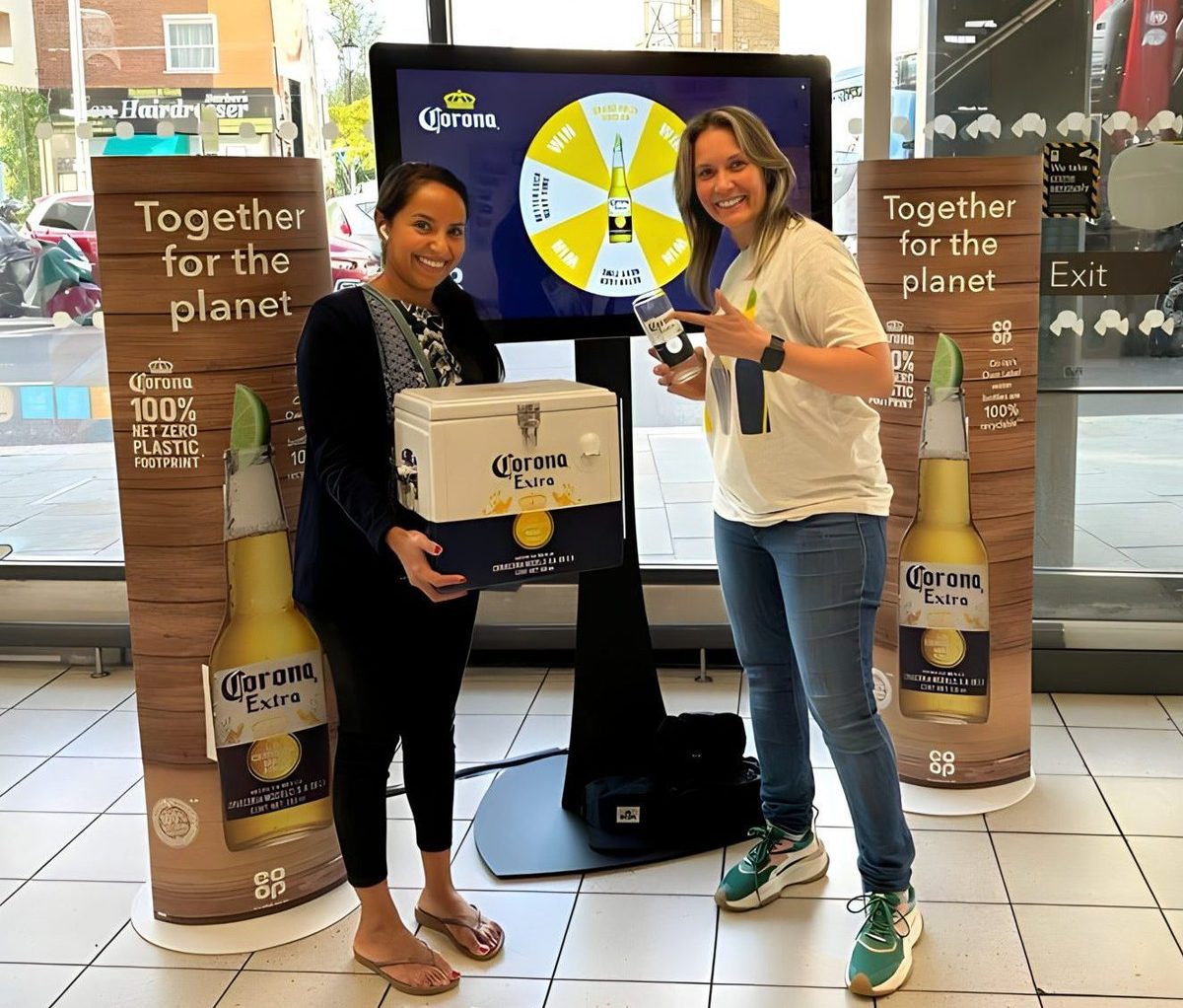 Two staff beside a Corona display in a Co-op store