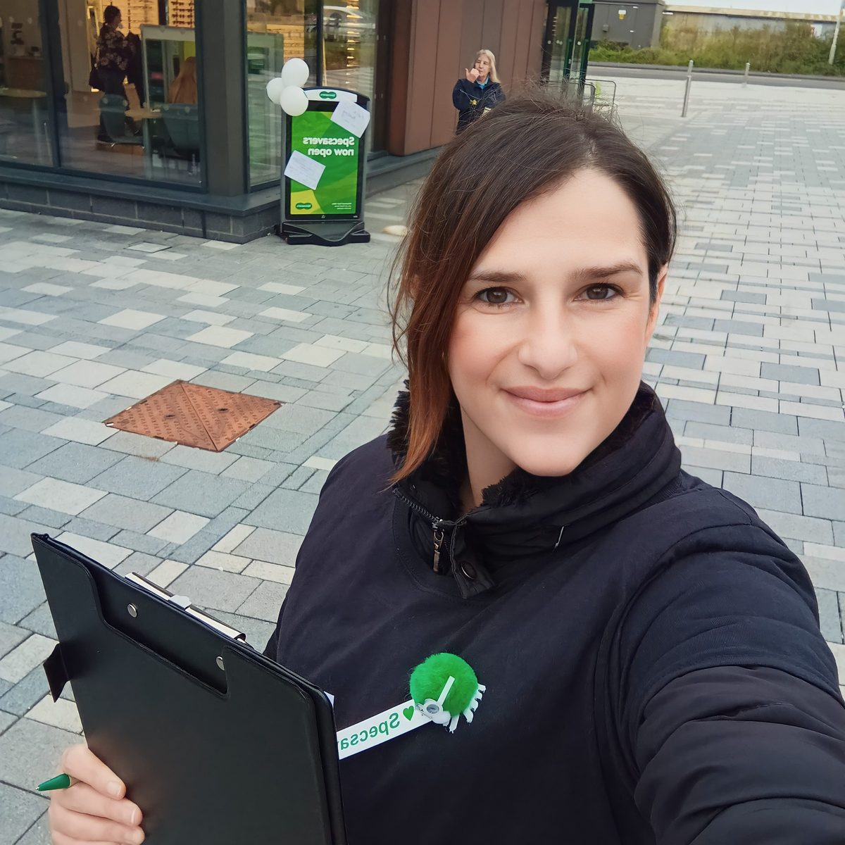 Staff member with a clipboard outside a Specsavers store