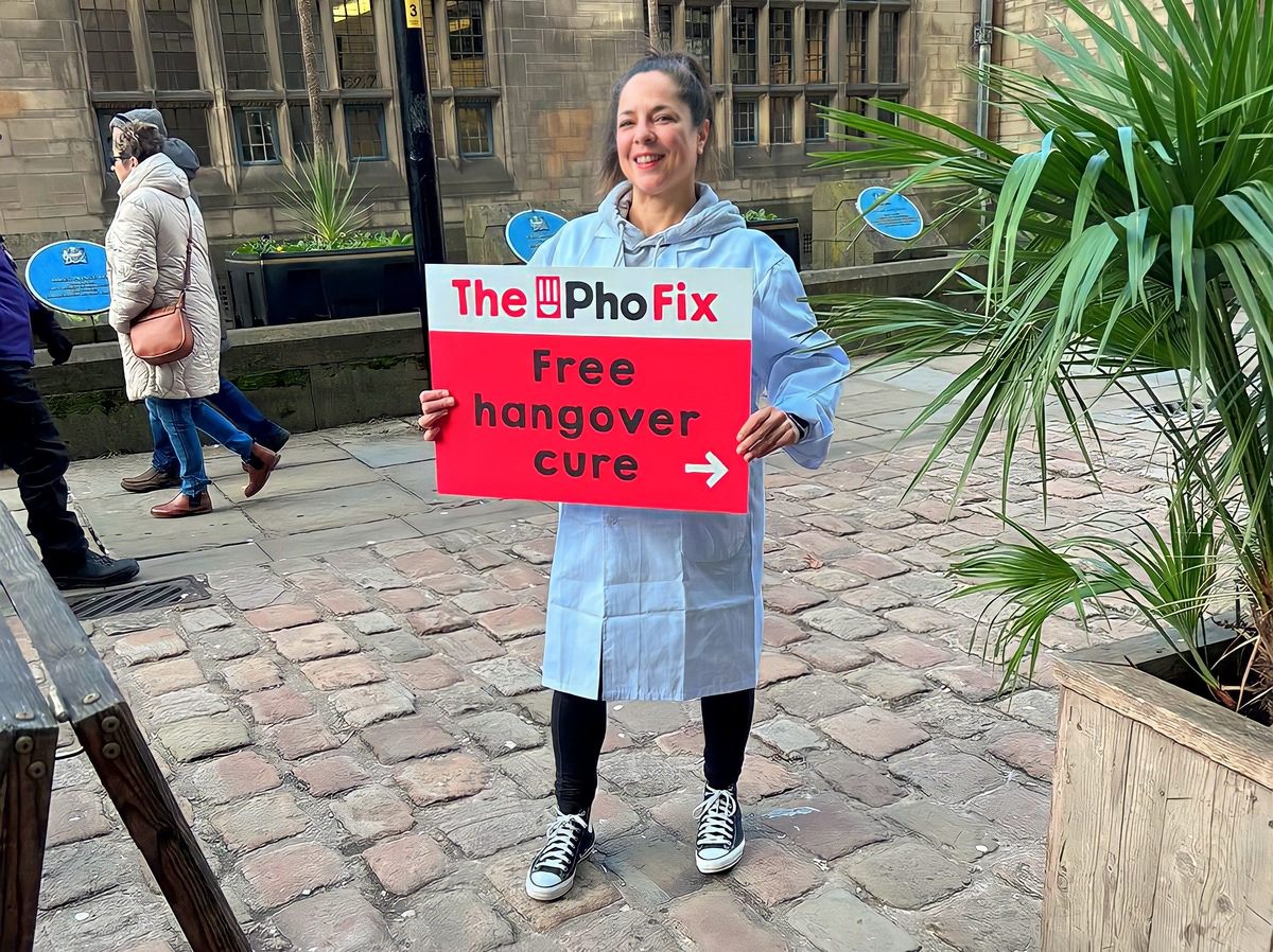 Promotional staff member with a sign for the Pho pop-up on a city street