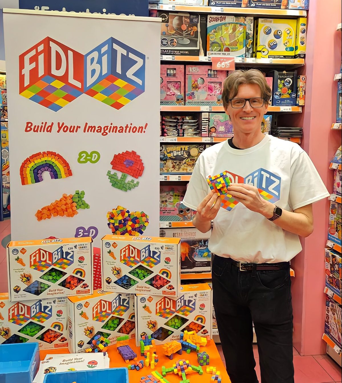 Bandai FidlBitz demonstrator holding the product beside the display in a toy store
