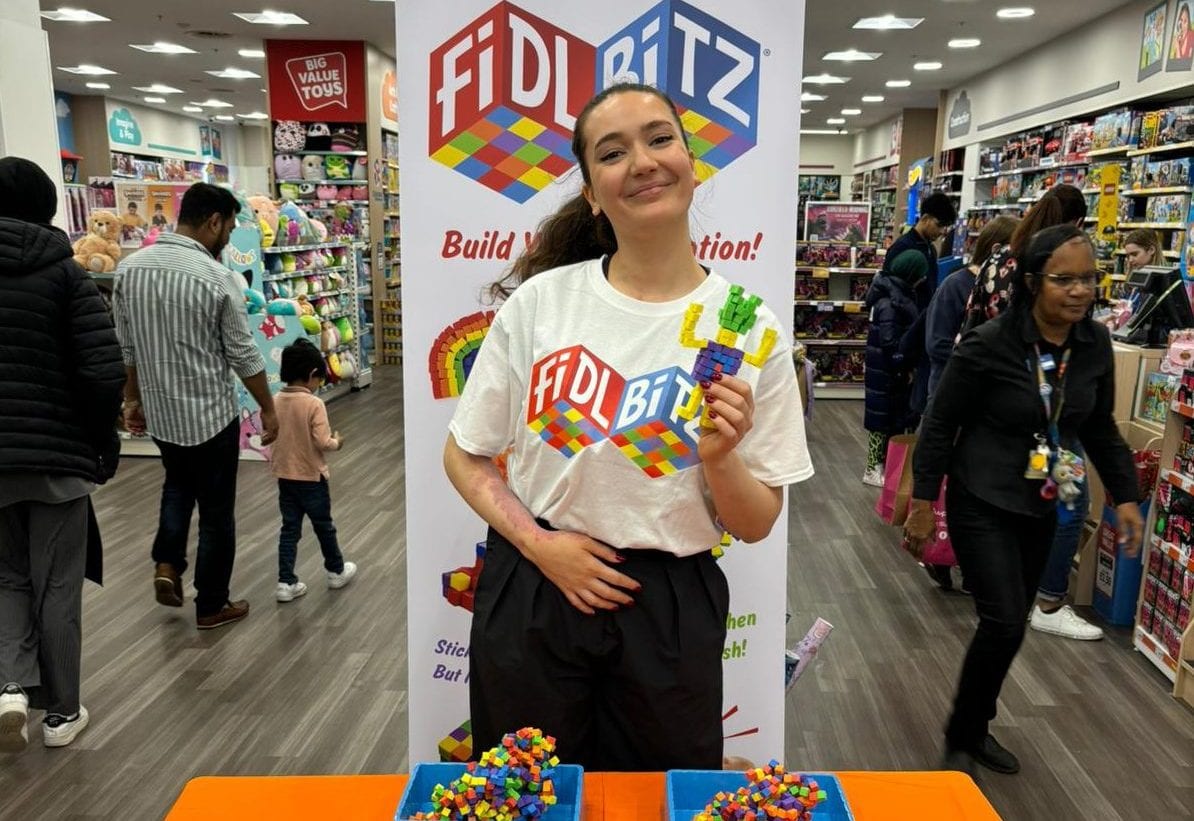 Staff member demonstrating FidlBitz toys in a toy store aisle