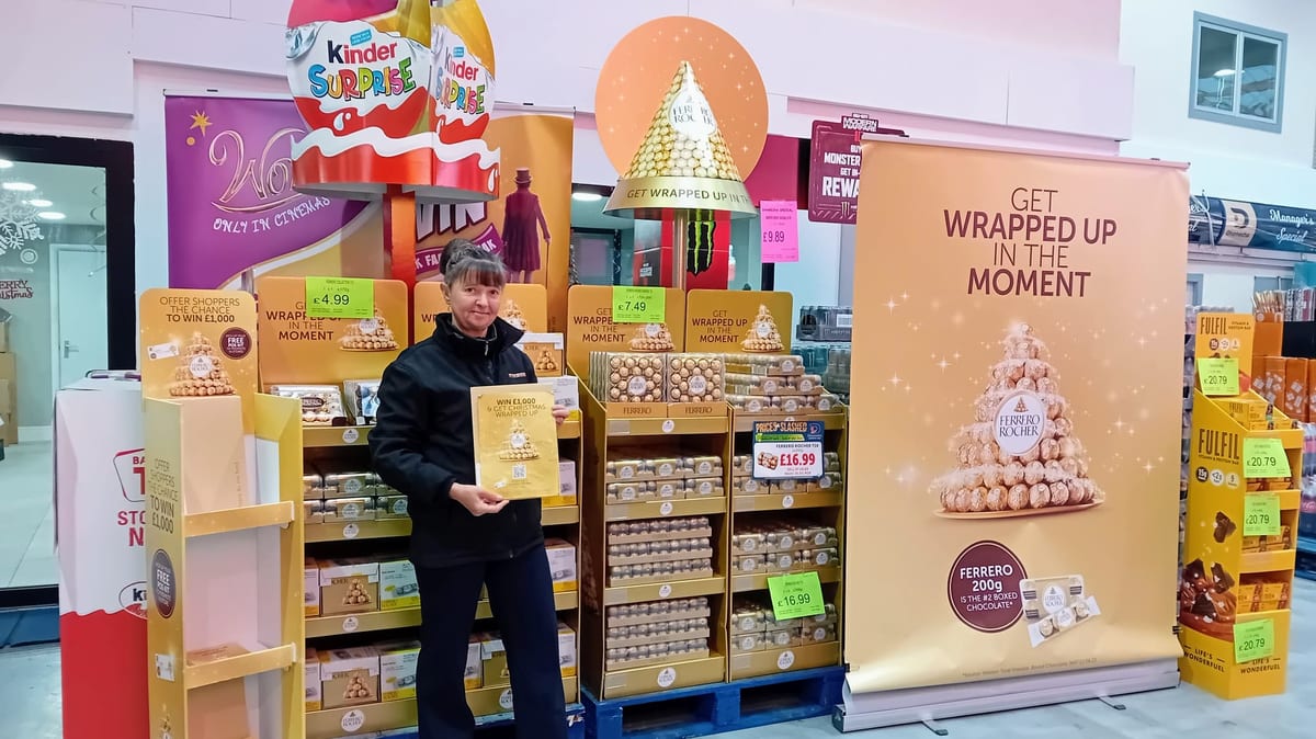 Merchandiser with a clipboard checking a Ferrero display in store