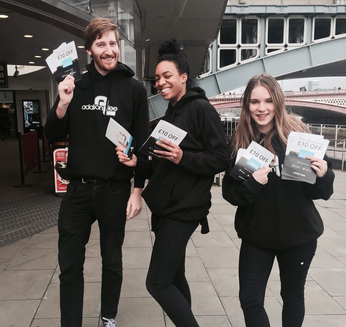 Addison Lee leafleting team in matching black kit outside a London train station
