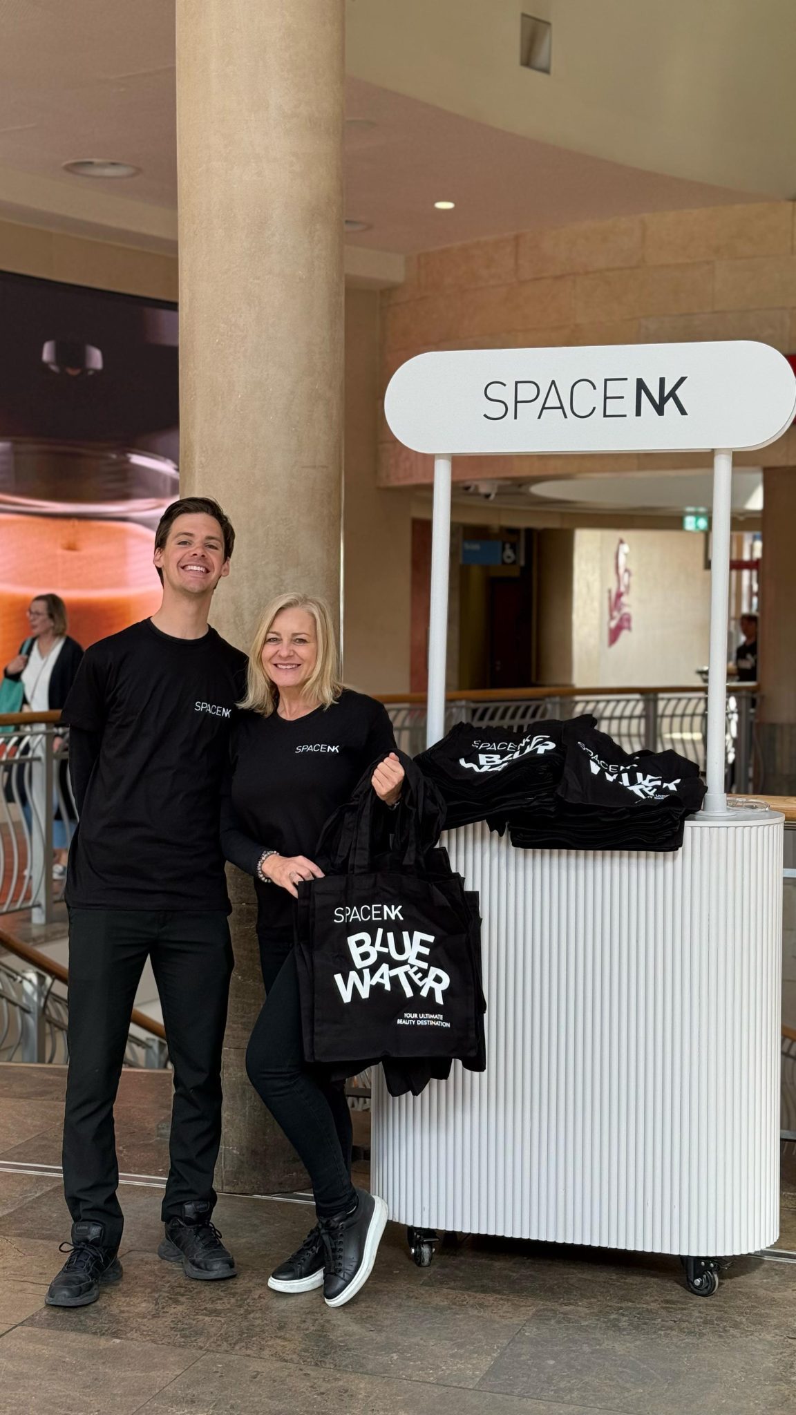 Two promotional staff beside a Space NK cart in Bluewater shopping centre