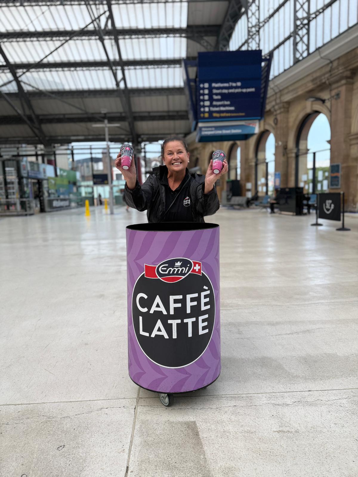 Emmi Caffè Latte sampling staff member with a branded bin on the Liverpool Lime Street station concourse