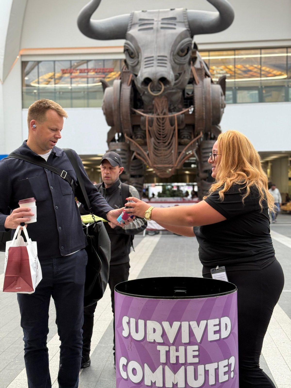 Emmi Caffè Latte sampling staff handing a drink to a commuter at Birmingham New Street
