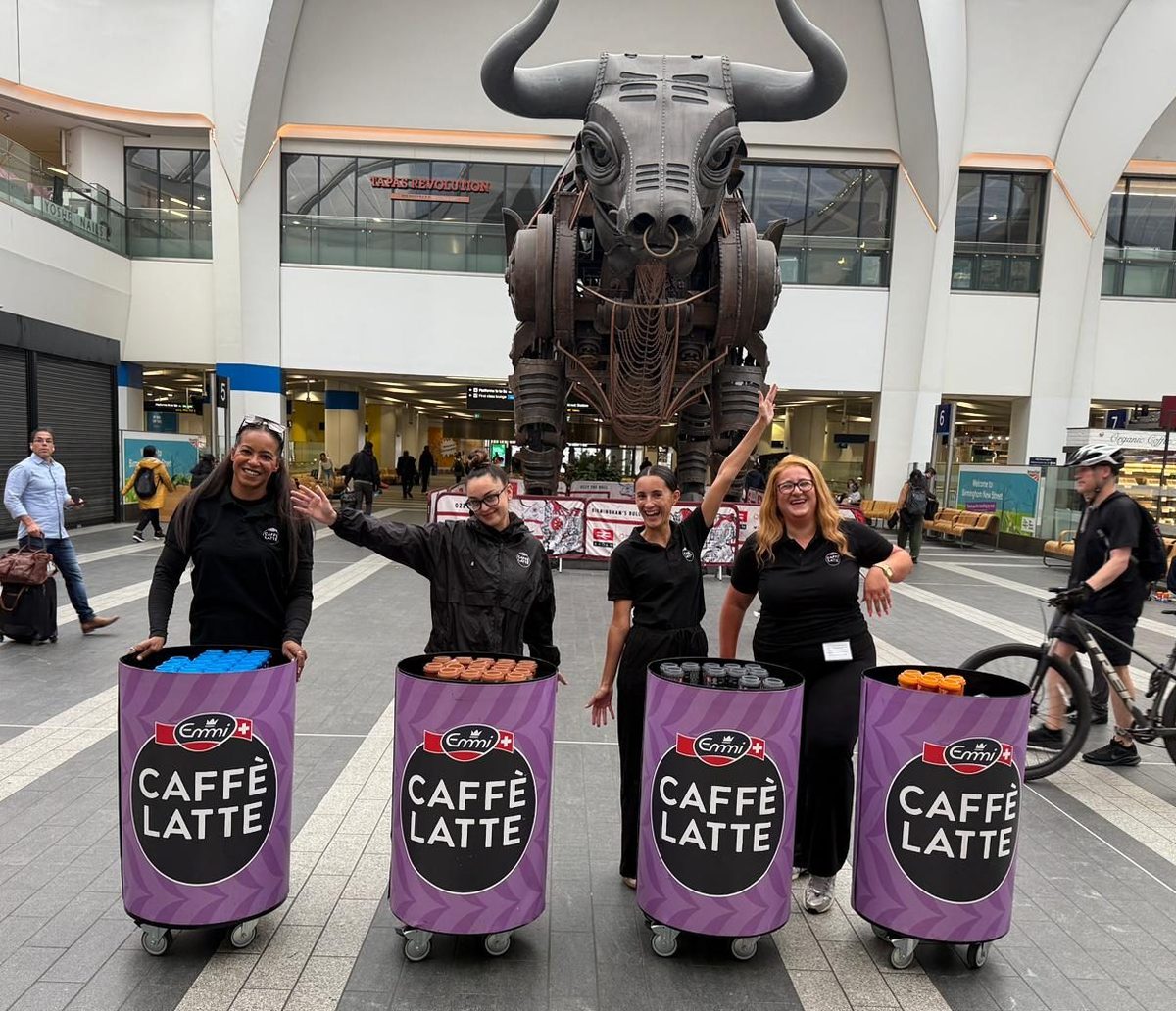 Emmi Caffè Latte sampling team in matching black kit with branded bins at Birmingham New Street