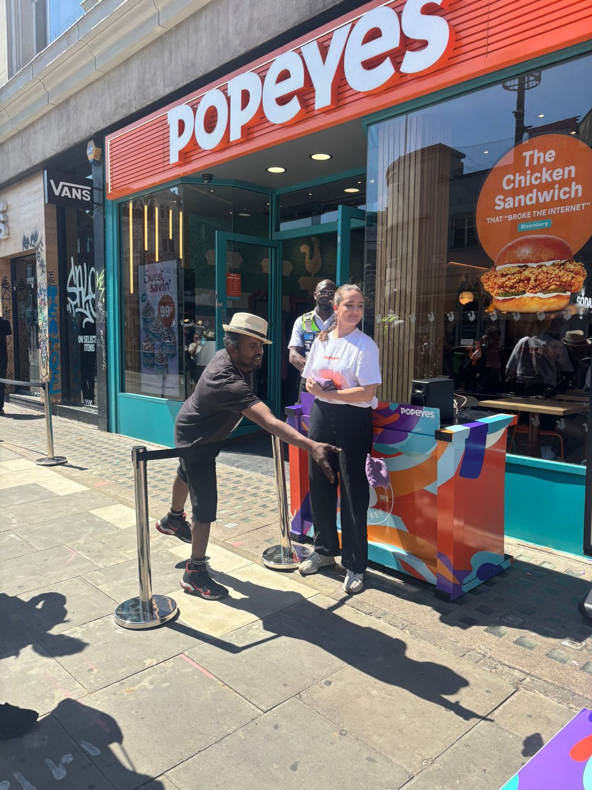 Staff member welcoming a customer at the door of the Popeyes restaurant in Milton Keynes