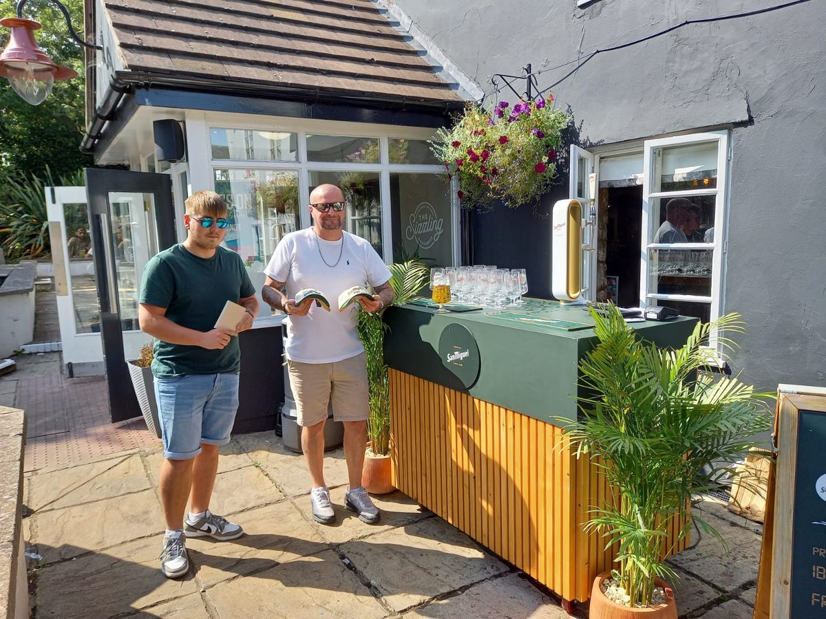 Staff pouring San Miguel Gold pints behind a branded bar at The Manor