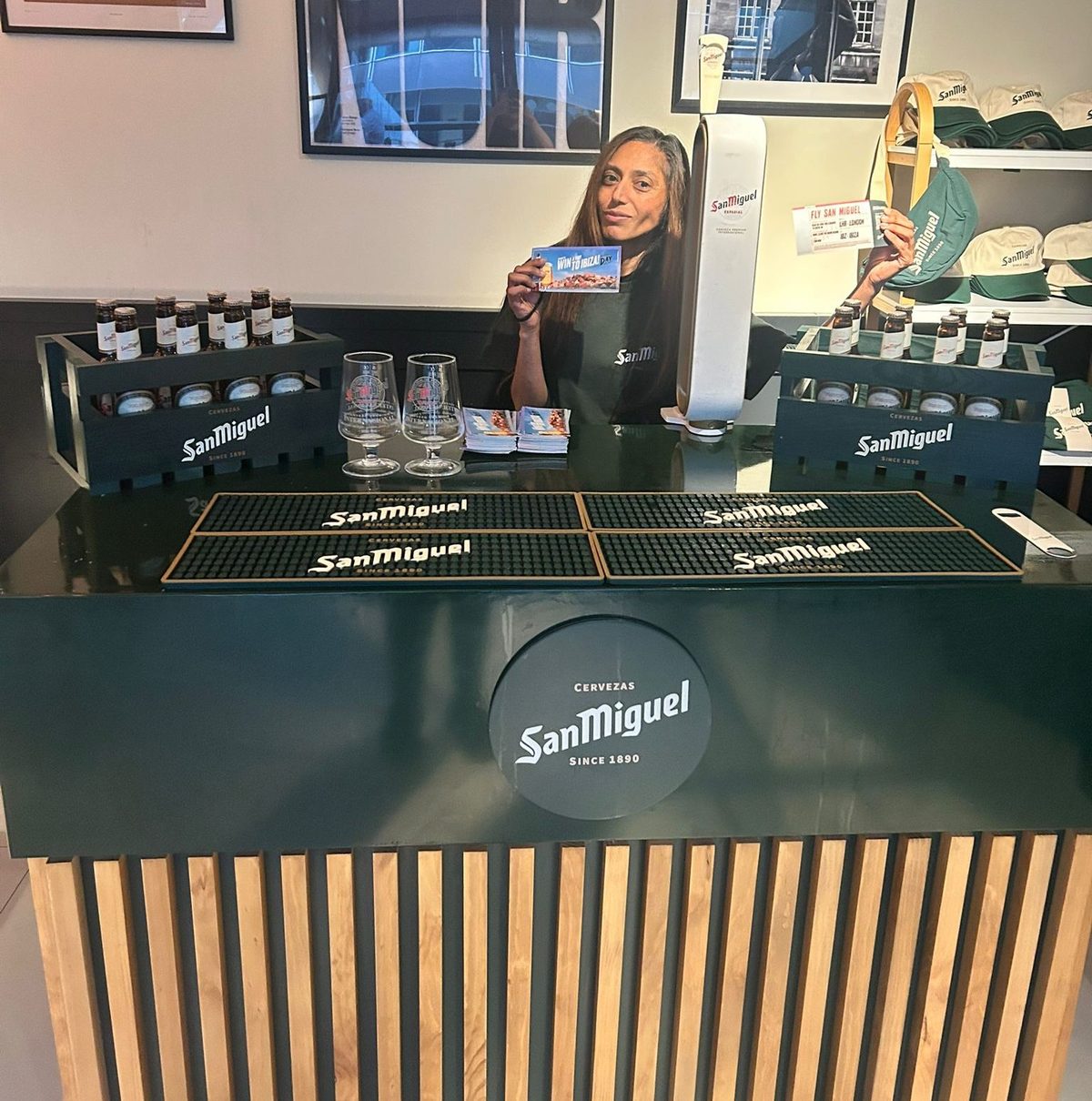Promotional staff behind a San Miguel bar holding a prize draw card