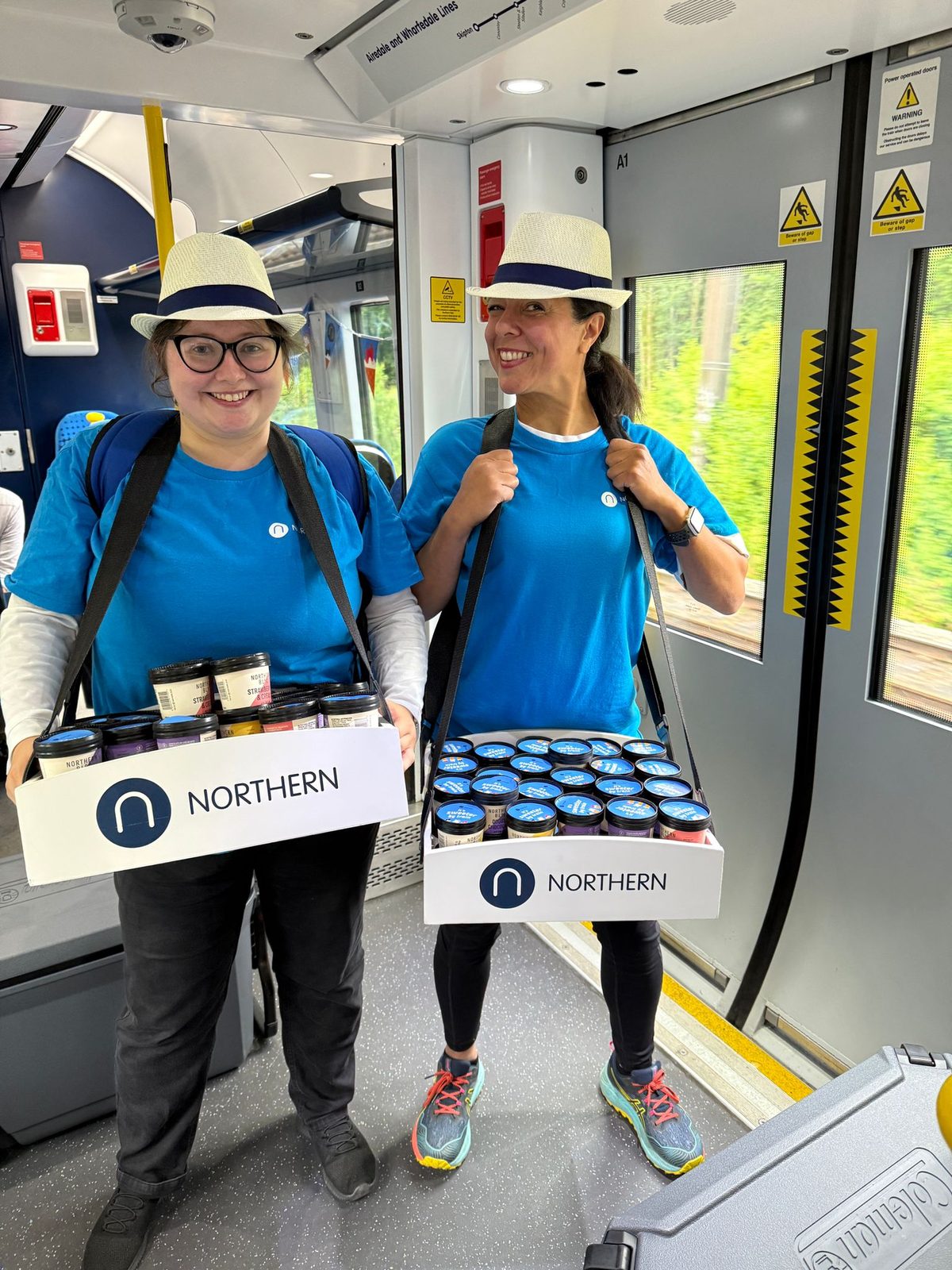 Two Northern Rail brand ambassadors carrying sample trays on a train