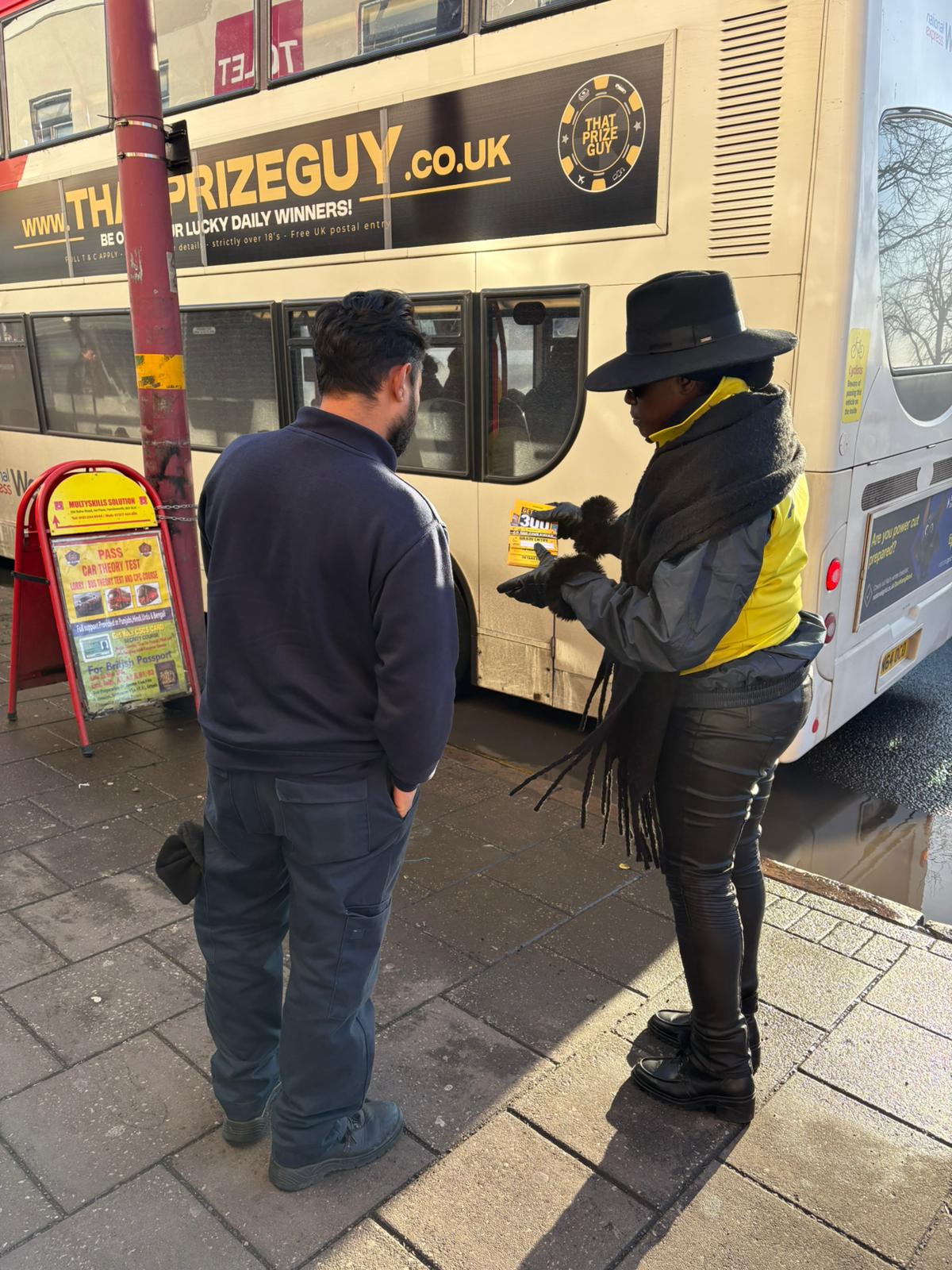 Admiral promotional staff member offering a flyer to a passer-by on the high street