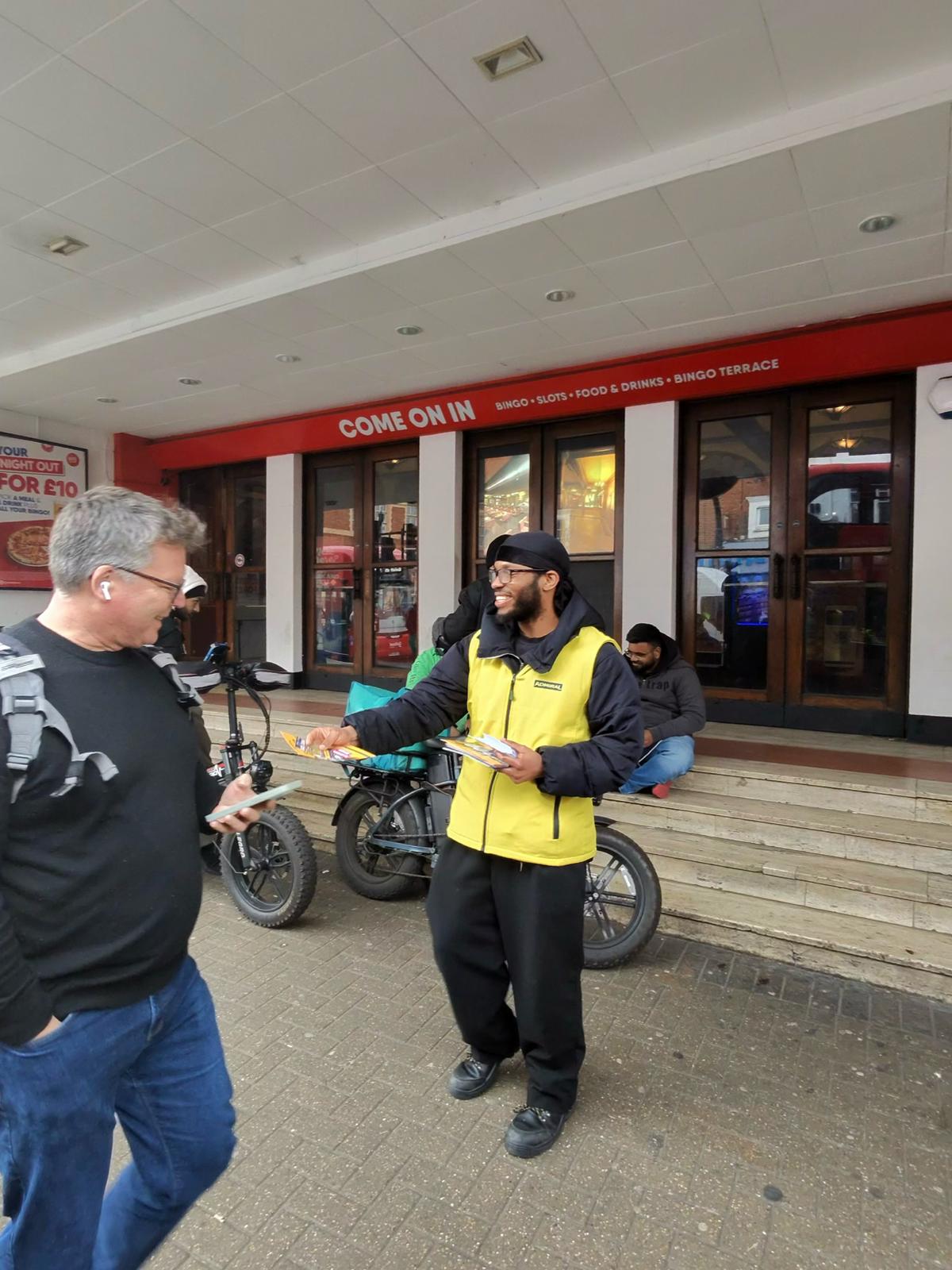 Admiral leafleting staff member handing a leaflet to a passer-by on the high street