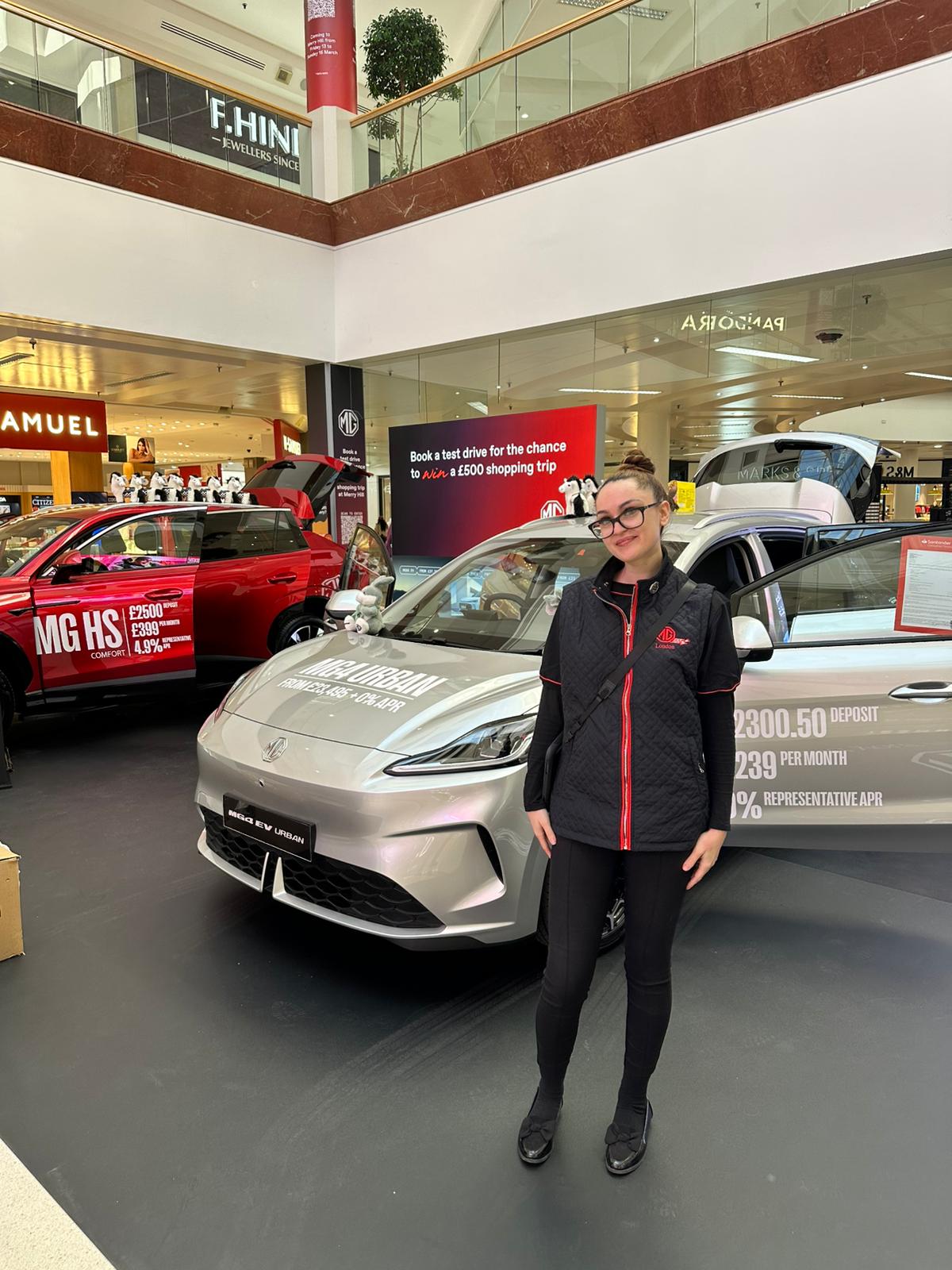 MG test drive brand ambassador beside a new model in a shopping centre