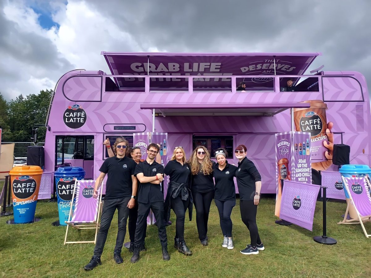Executional promotional team beside the Emmi Caffe Latte bus at an outdoor event in Brighton