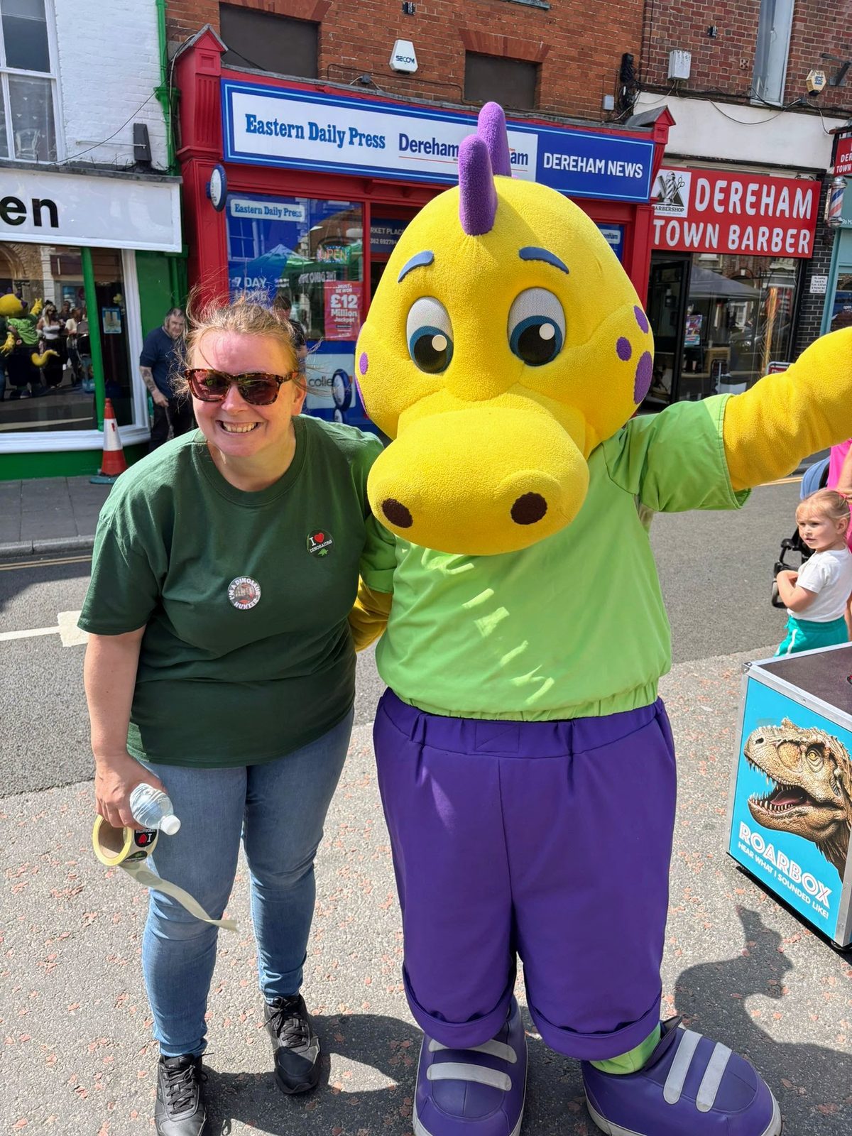 event staff welcoming families beside the Dino Bus in Dereham town centre