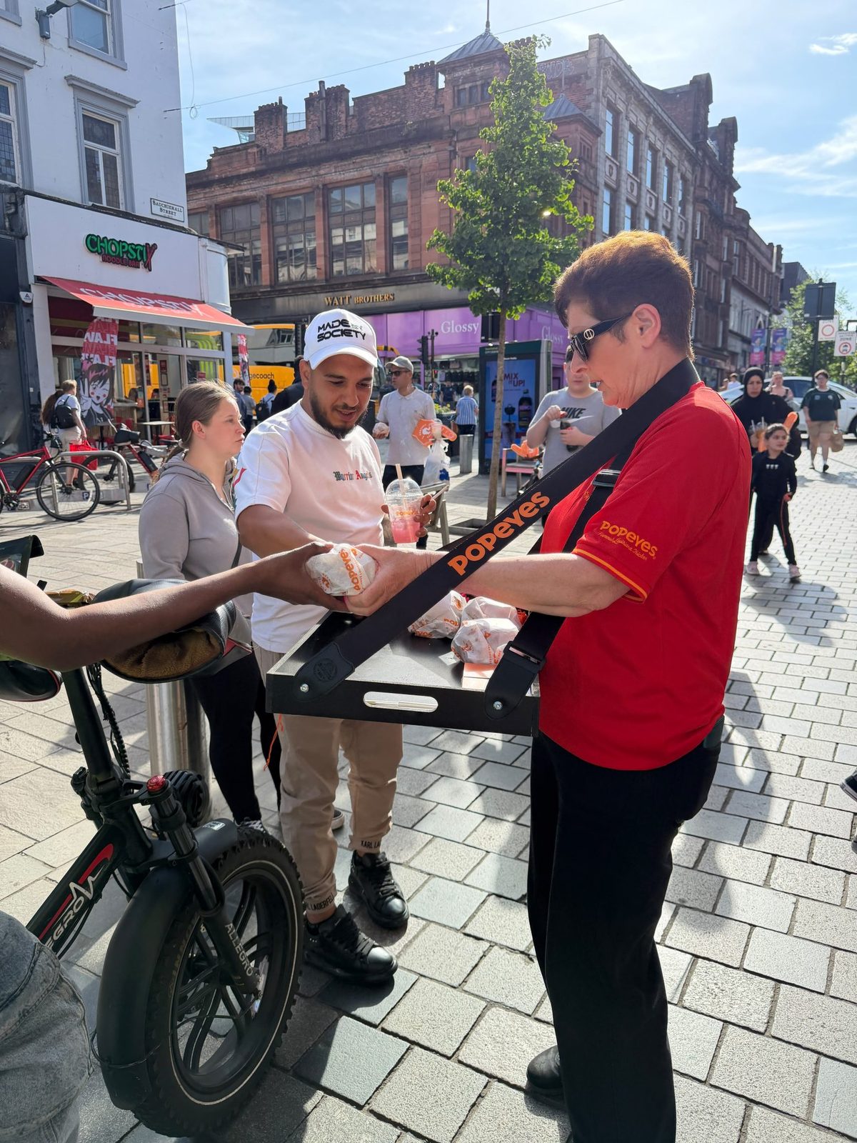 Popeyes brand ambassador with a sample tray on a branded bike in a Glasgow street