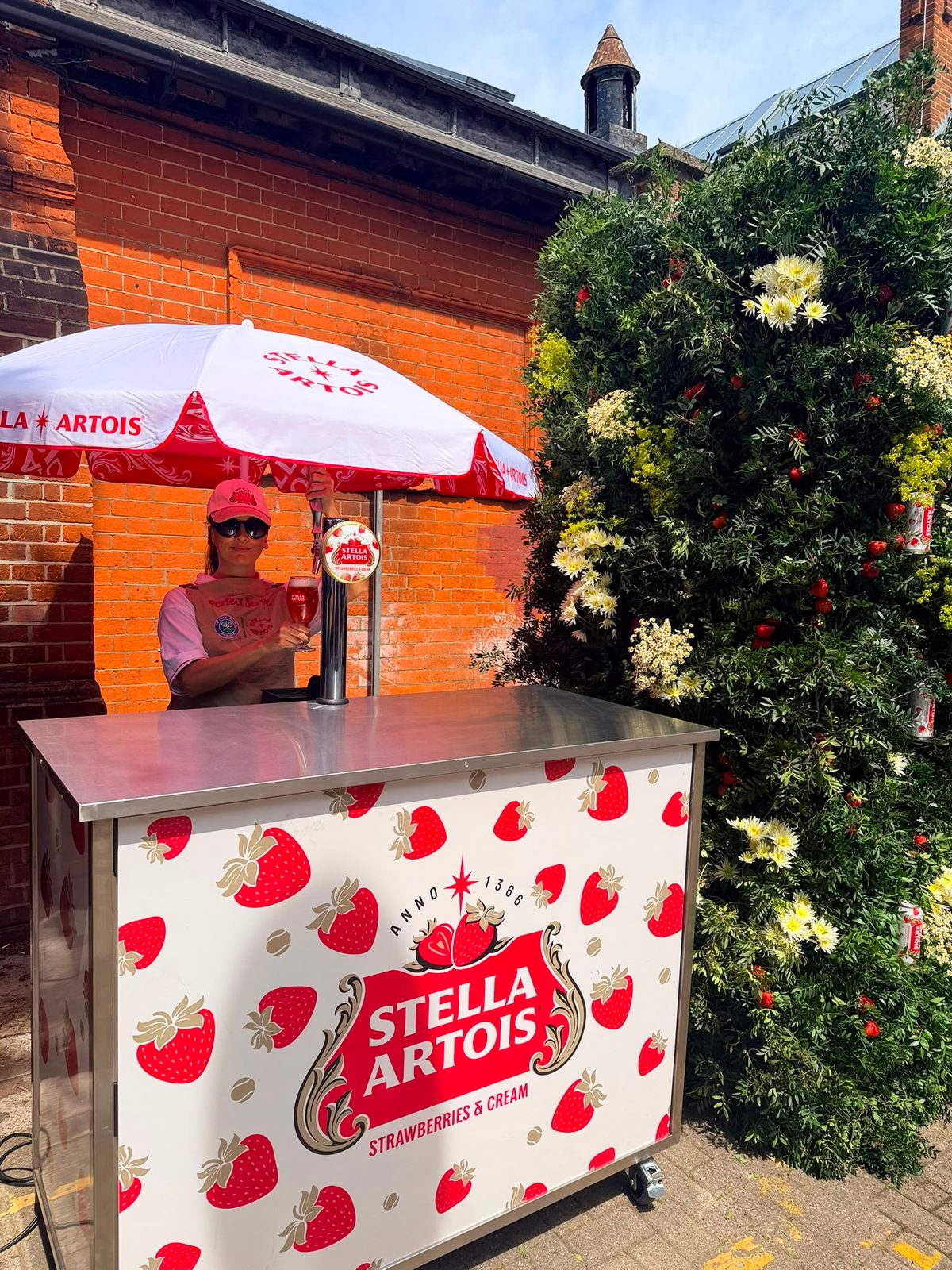 Brand ambassadors beside a foliage-covered strawberry wall at The Alexandra in Wimbledon
