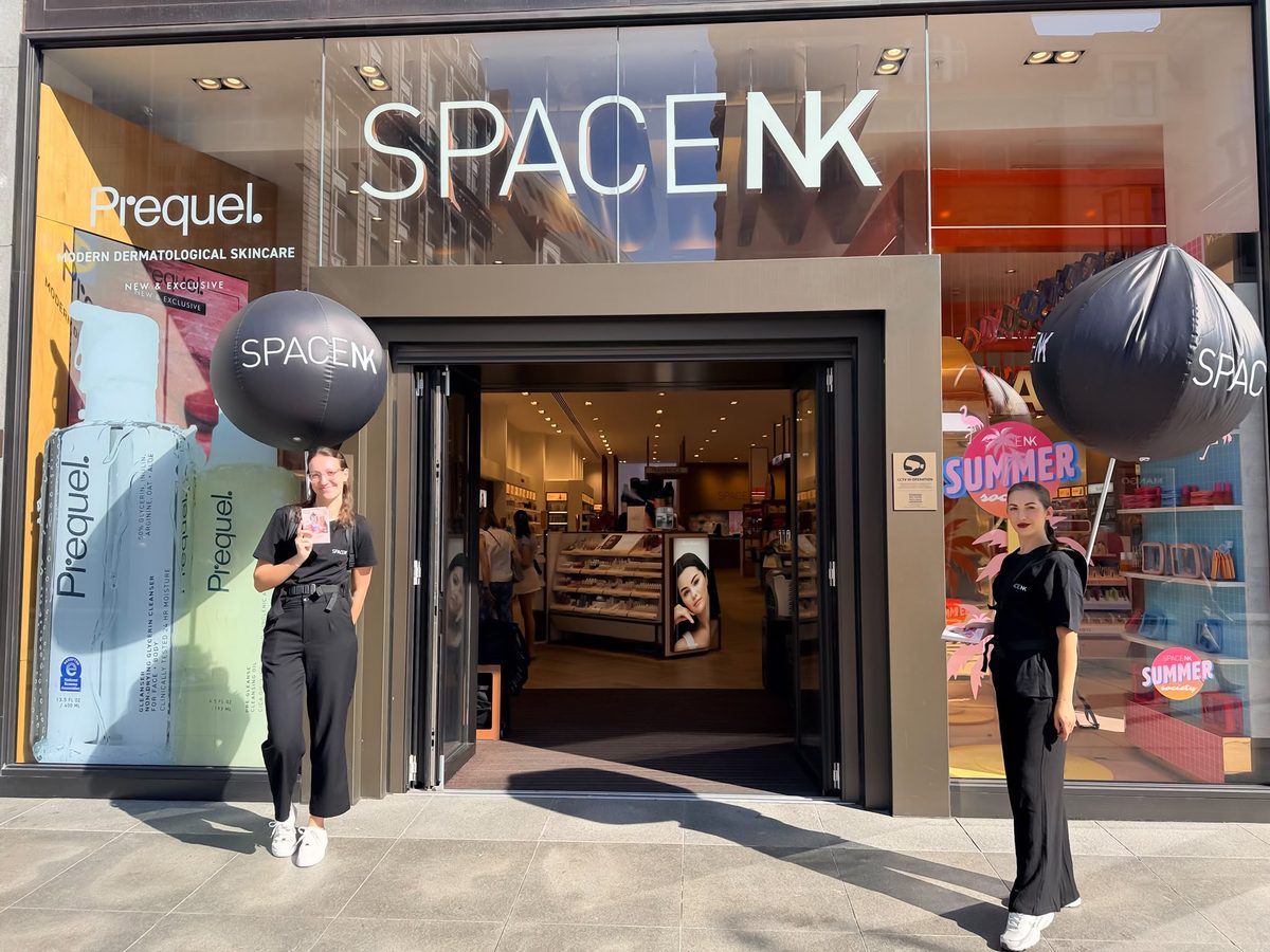 Two brand ambassadors with black Space NK balloons at a store entrance