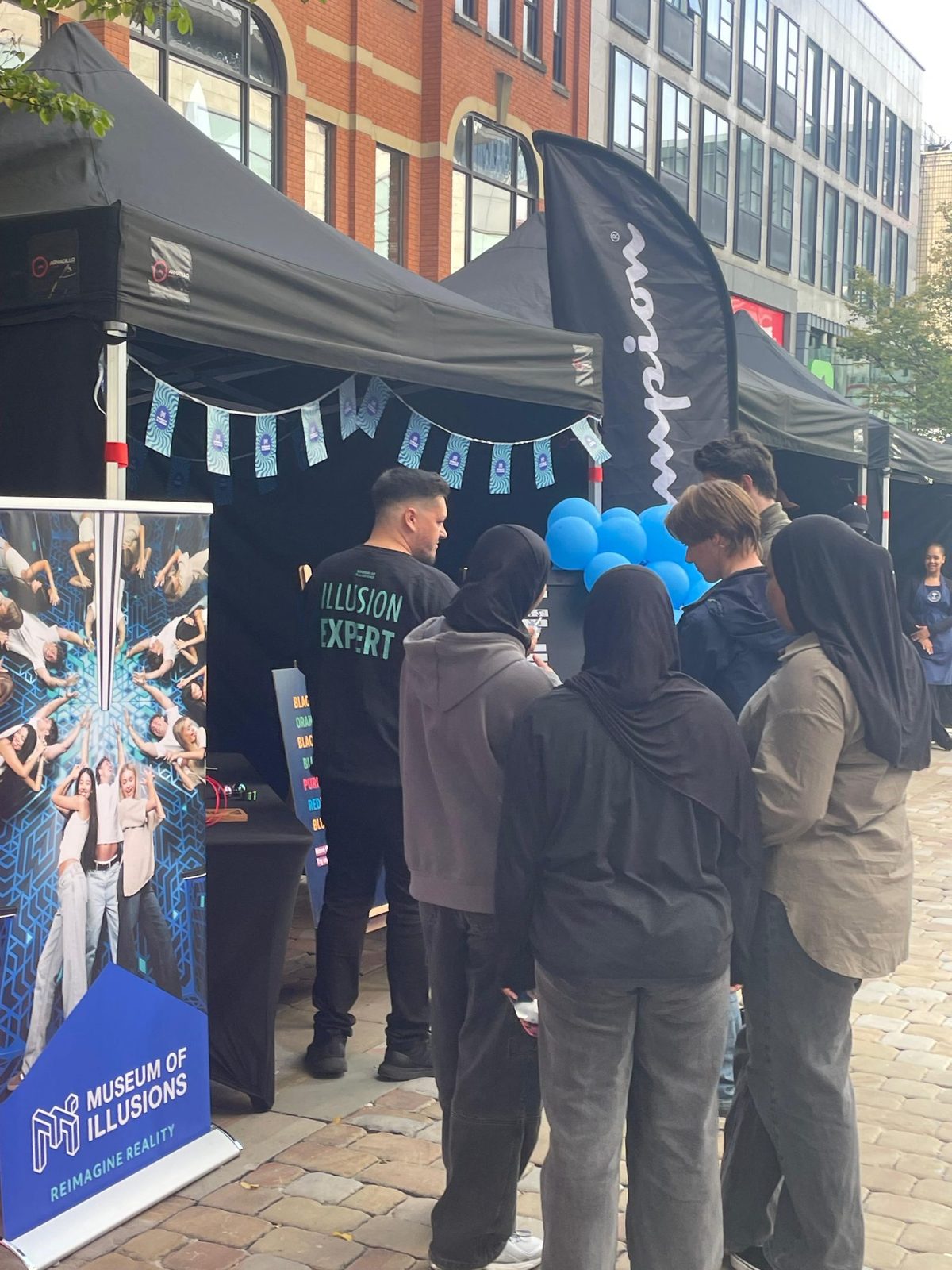 Museum of Illusions leafleting team at a branded gazebo on a shopping street