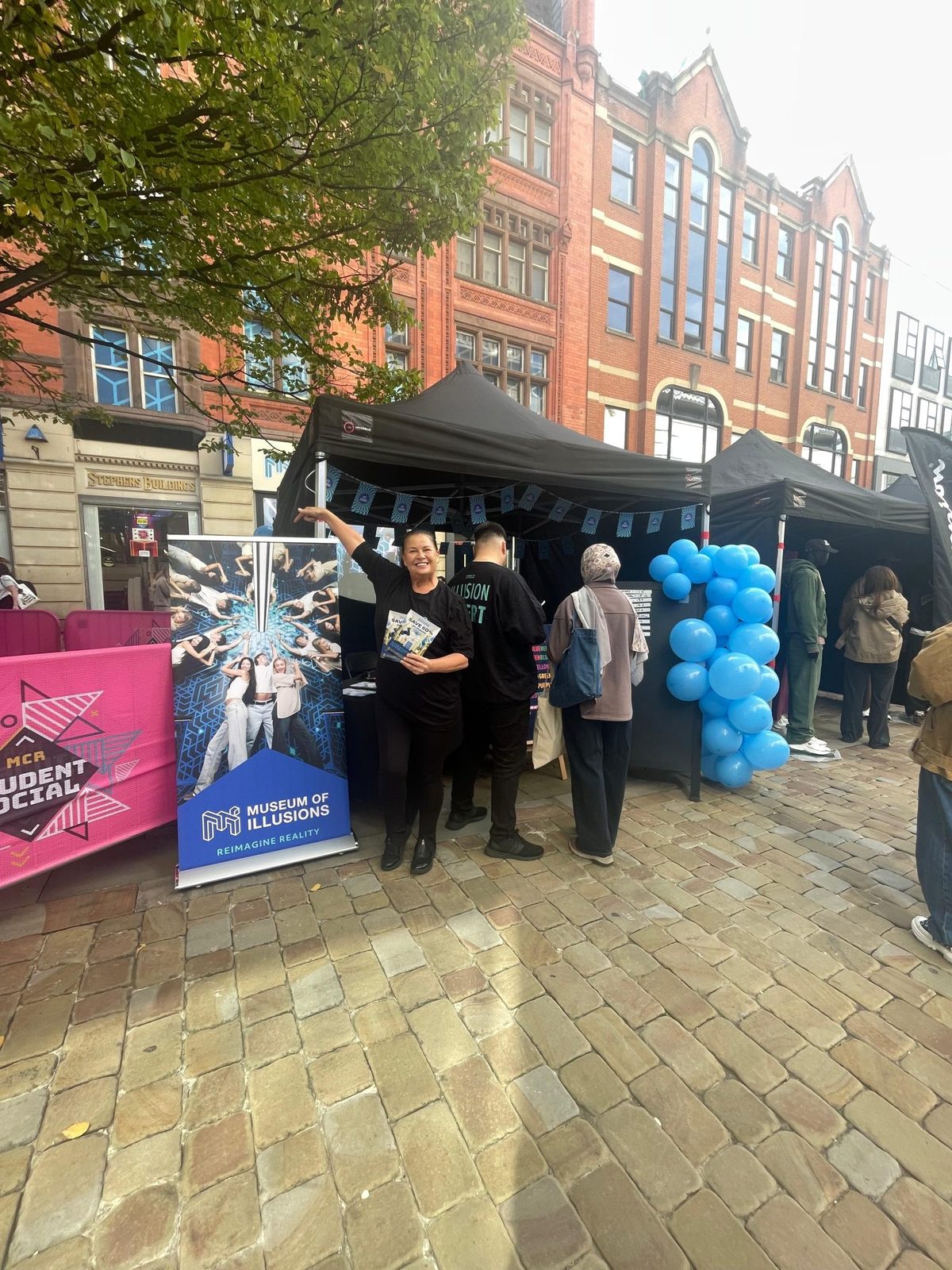 Museum of Illusions leafleting team at a branded gazebo on a town centre street