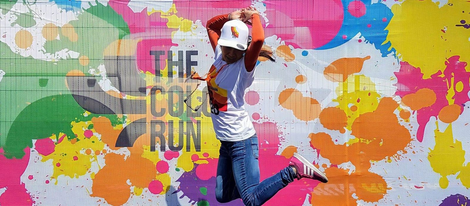 Executional team member jumping in front of a colourful event banner