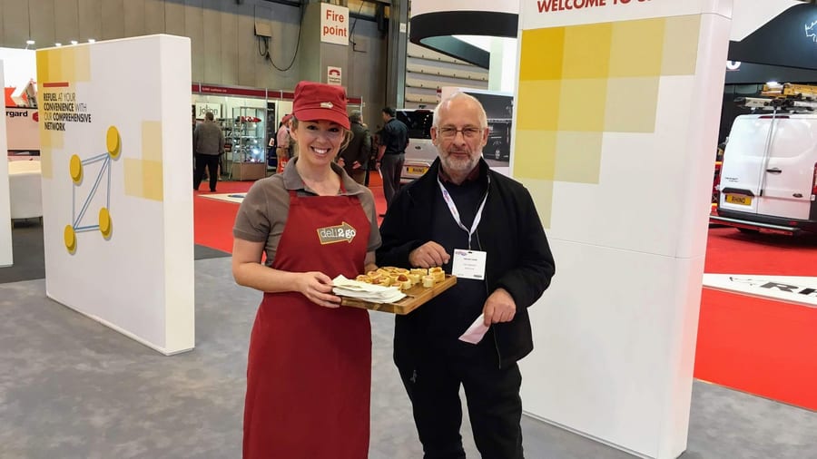 EXECUTIONAL sampler offering food samples to a visitor at a trade show