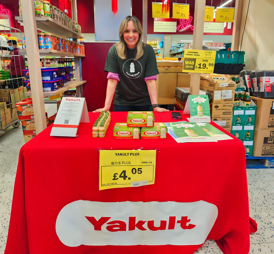 EXECUTIONAL team member beside shelf-edge pricing for Yakult in a supermarket