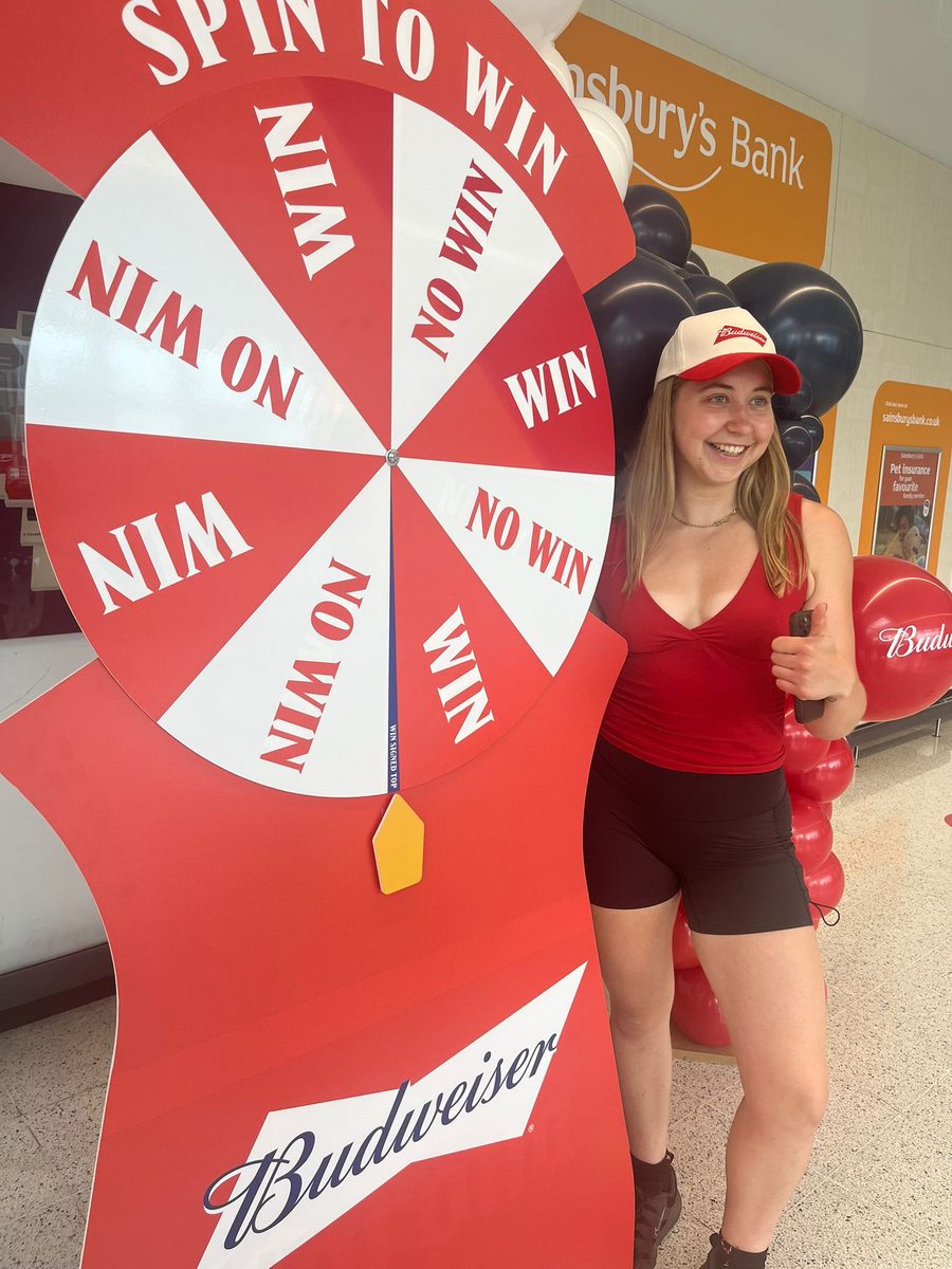 EXECUTIONAL team member beside a Budweiser free-standing unit in a Sainsbury's store